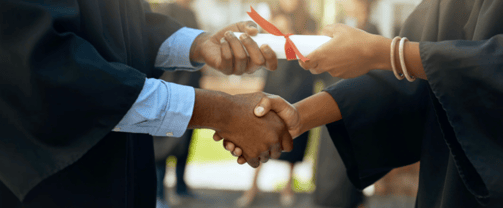 graduate and professor shaking hands during graduation