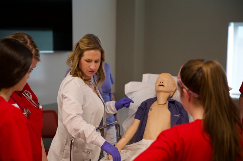 sacred heart university students practicing nursing on a doll